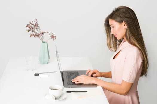 a woman typing on a laptop with a cup of coffee